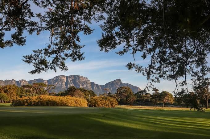 Golf green framed by pine trees below Table Mountain in the Western Cape